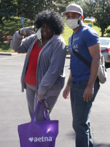 volunteer with food delivery sack, provided by Aetna Insurance, walking with founder of Ravik Foundation